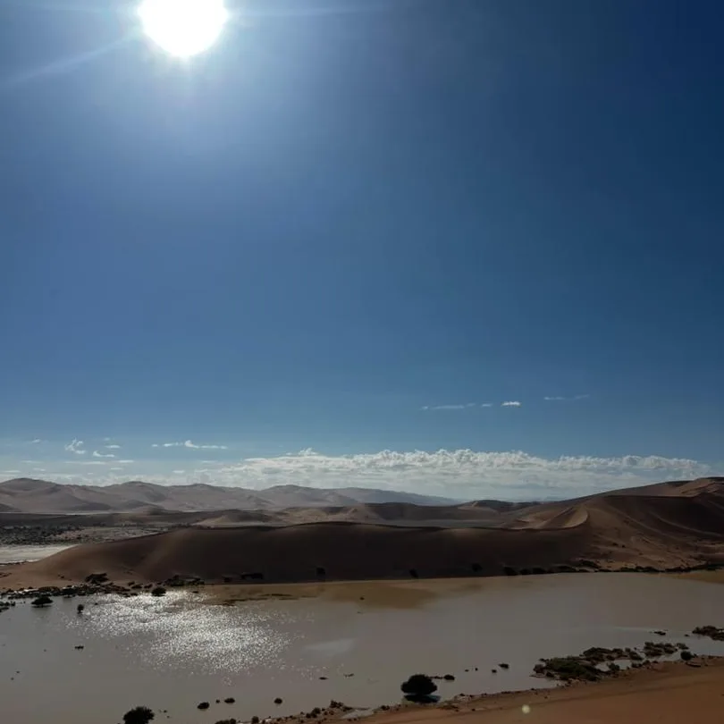 Die son wat oor duine bo 'n dun laag water op die sand bars